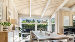 A modern kitchen with a dining area, wooden ceiling, and large windows.