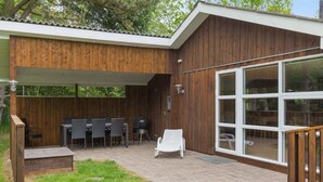 A covered patio with outdoor furniture, a grill, and a large sliding glass door leading to an outdoor area.