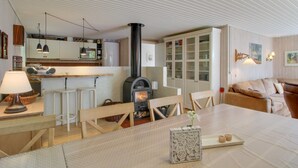 A cozy living room with a fireplace, a dining area with a table and chairs, and a kitchen with modern appliances and wooden cabinets.