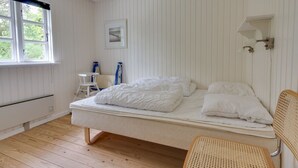 A room with a bed, a small table, a chair, and a window.