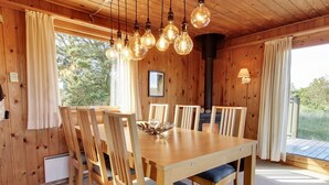 Comedor de madera con una mesa y sillas, una lámpara colgante y una chimenea.