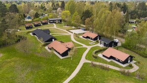 An aerial view of a residential area with multiple houses, green lawns, and a clear sky. - "Nafni" - 200m from the sea by Interhome (Væggerløse)