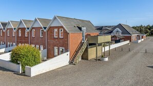 A row of brick buildings with a gravel driveway and a wooden staircase leading to a covered area.