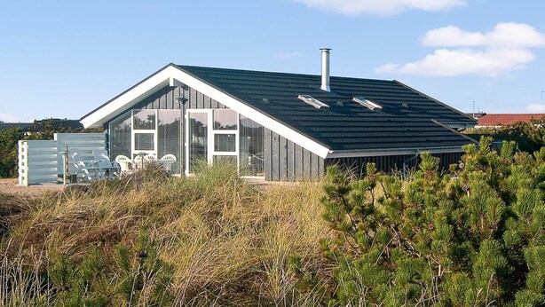 Et moderne hus med skrå tag, store vinduer og en skorsten.