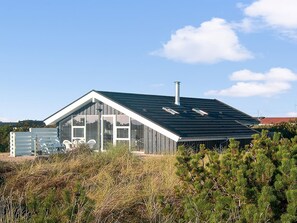 Ett modernt hus med ett sluttande tak, stora fönster och en skorsten.
