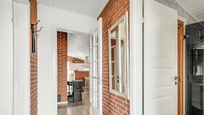 A hallway with a brick wall, white doors, and a glass shower door.