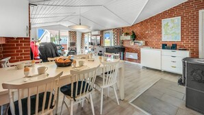 A spacious kitchen with a dining area, featuring a brick wall, white cabinetry, and a large dining table with chairs.