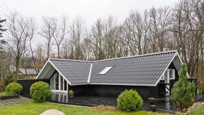 Une maison moderne avec un toit en pente, de grandes fenêtres et une pelouse bien entretenue.