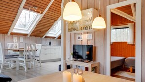 Un intérieur de chalet chaleureux comprenant un coin repas, une cuisine et un téléviseur.