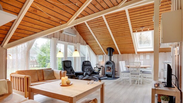 Un vaste espace de vie doté d’un haut plafond, de poutres apparentes, d’une cheminée et de sièges confortables.