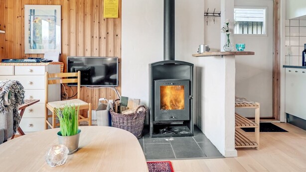 Ein modernes Wohnzimmer mit Holzvertäfelung, einem schwarzen Kamin, einem Flachbildfernseher und einem Essbereich mit Tisch und Stühlen.