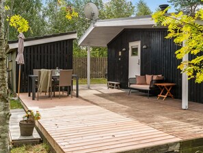 Une terrasse en bois avec des meubles d’extérieur, un espace salon couvert et une antenne parabolique.