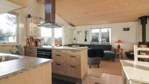 Eine moderne Küche mit Holzausstattung, einer zentralen Kochinsel und einem großen Fenster.