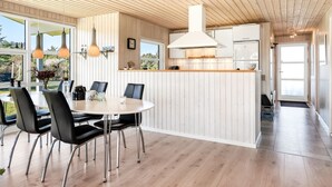 Une cuisine moderne dotée d’un îlot central, d’un plafond en bois et de grandes fenêtres.