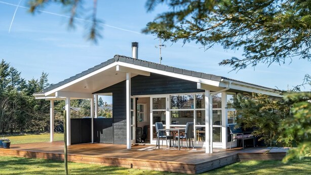 Une maison moderne dotée d’un patio couvert, d’une terrasse et d’une grande porte vitrée donnant sur l’intérieur.