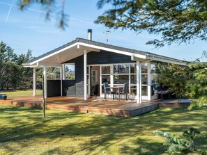 A modern house with a covered patio, a deck, and a large glass door leading to an interior space.