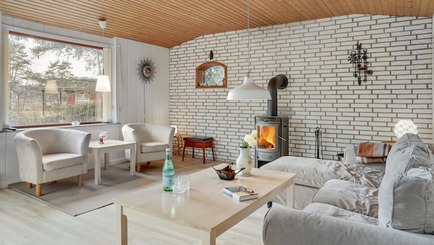 A modern living room with a brick wall, a wooden ceiling, and a wood-burning stove. - "Herly" - 50m from the sea by Interhome (Hals)