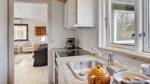 A compact kitchen with a stove, sink, and a window. - "Herly" - 50m from the sea by Interhome (Hals)