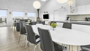 A modern kitchen with a central island, white cabinetry, and a large window overlooking a cityscape.