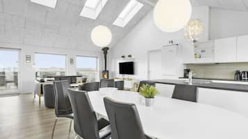 Une cuisine moderne dotée d’un îlot central, de meubles blancs et d’une grande fenêtre donnant sur un paysage urbain.