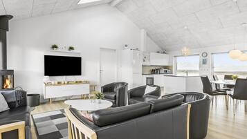 Un salon moderne doté d’une cheminée, d’un téléviseur à écran plat, d’un canapé et d’un coin repas avec des chaises et une table.
