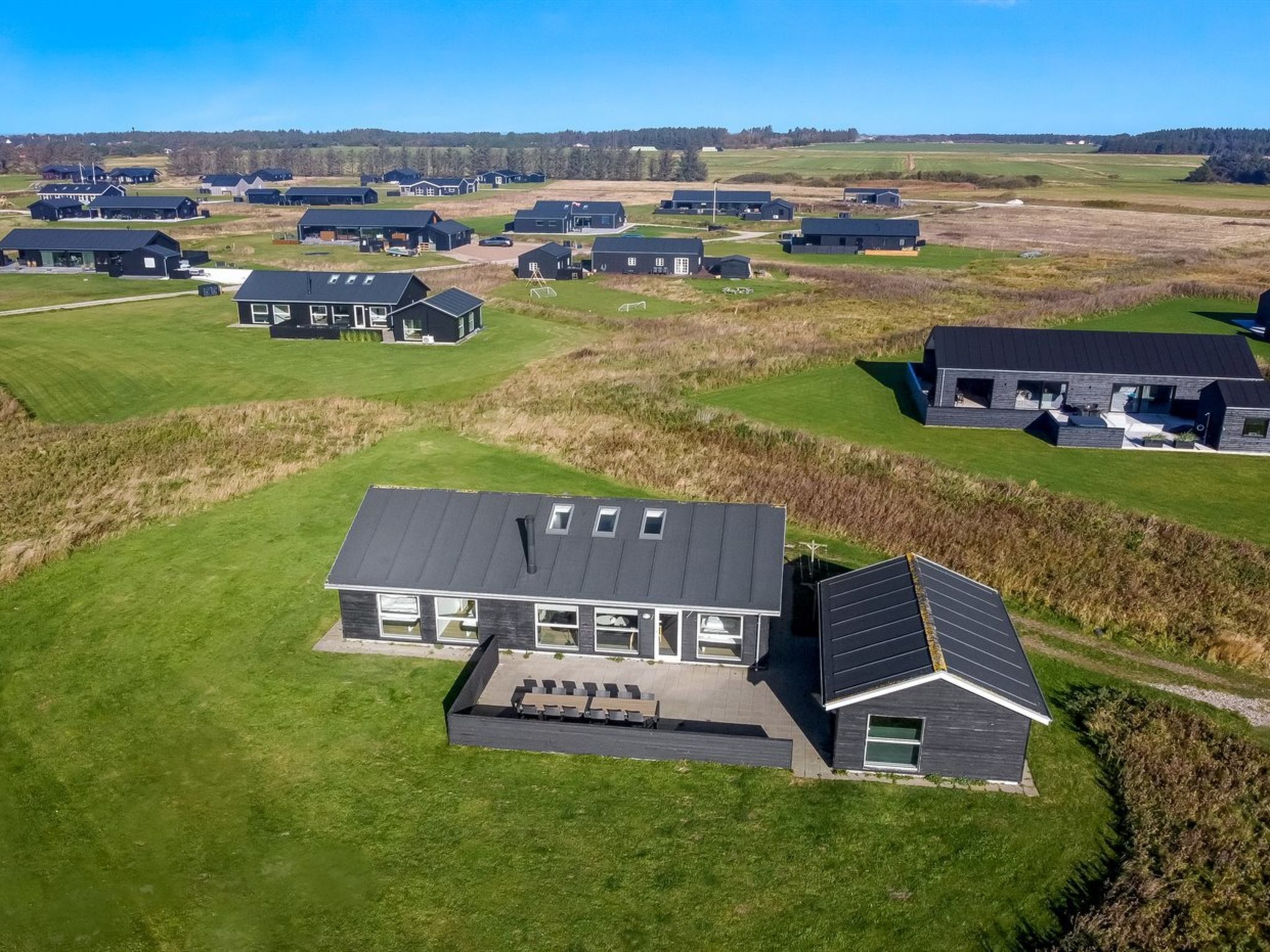 Et moderne boligområde med flere huse, mørke tage og store vinduer.