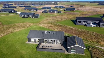 Et moderne boligområde med flere huse, mørke tage og store vinduer.
