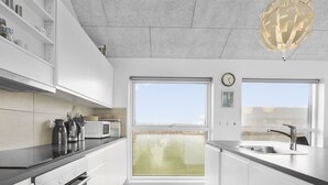 A modern kitchen with white cabinetry, a built-in oven, a microwave, and a large window offering a view of the outdoors.