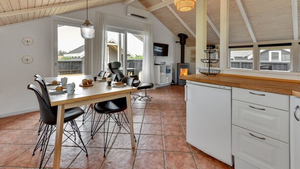 Una cocina moderna con techo de madera, comedor con sillas negras y un amplio ventanal.
