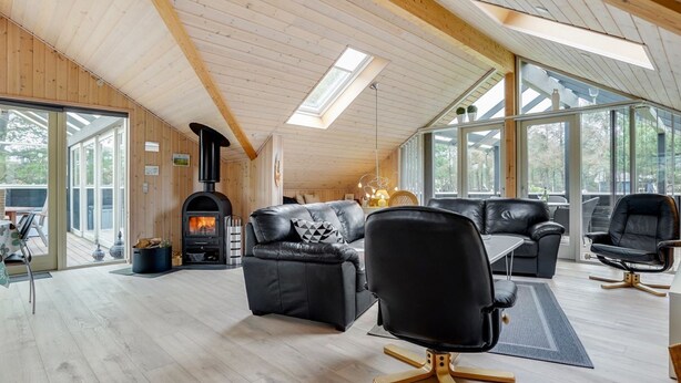Amplia sala de estar con chimenea, mobiliario de cuero y ventanas grandes que ofrecen luz natural y vistas.