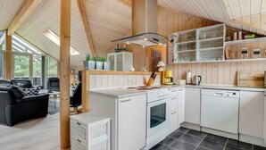 Una cocina moderna con armarios blancos, una isla central y una zona de comedor con un sofá de cuero negro.