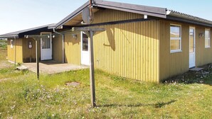 En envåningsbyggnad i trä med ett sluttande tak, en satellitparabol och en liten veranda.