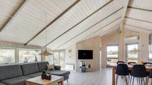 A spacious living area with a large sofa, a coffee table, and a dining table with chairs. A flat-screen TV is mounted on the wall, and there are large windows providing natural light. - "Estella" - 500m to the fjord by Interhome (Hvide Sande)