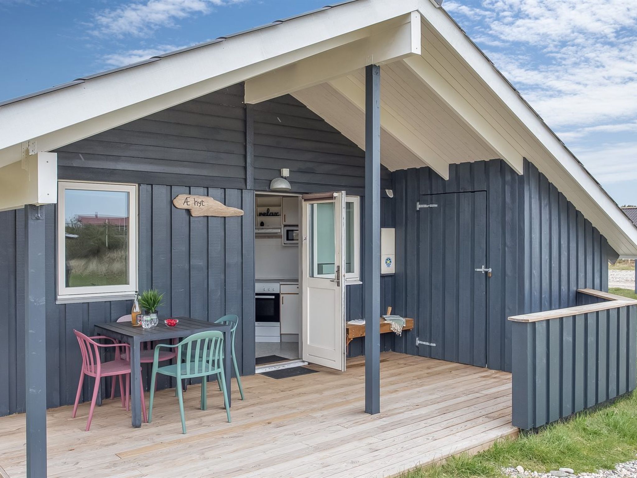 A modern, compact cabin with a dining area, a kitchenette, and a small porch.