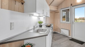 A modern kitchen with white cabinets, a stainless steel sink, and a potted plant on the counter. - "Estella" - 500m to the fjord by Interhome (Hvide Sande)