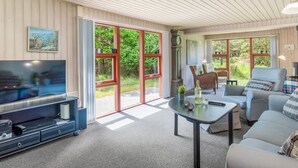 Ein geräumiges Wohnzimmer mit Fernseher, Couch, Couchtisch und Essbereich.