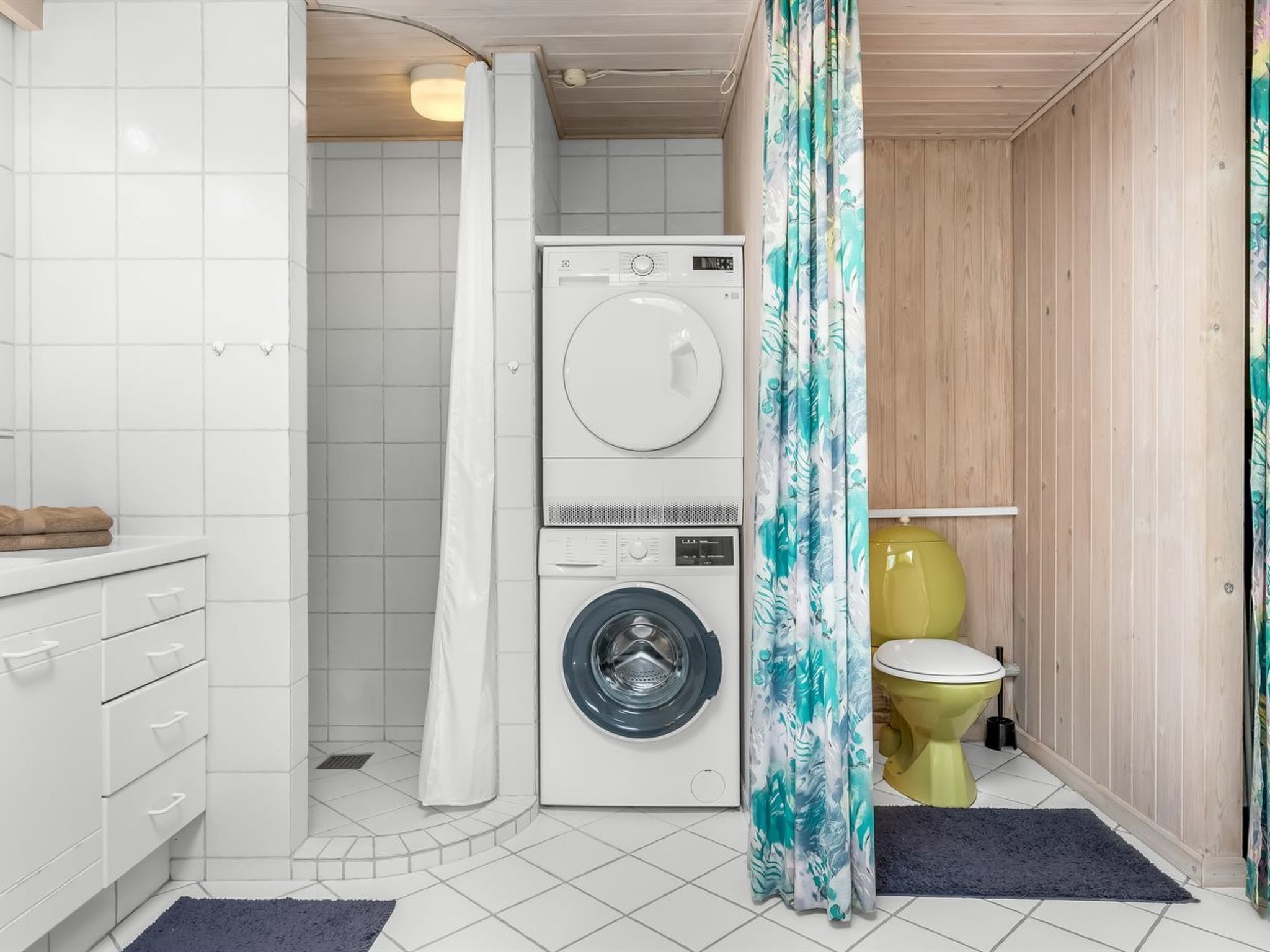 Un baño pequeño con lavadora, inodoro y cortina de ducha.
