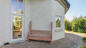 Een modern gebouw met grote ramen en een houten bankje buiten.