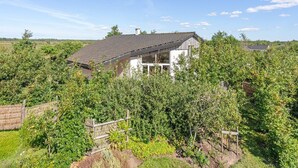 Een huis omringd door weelderige begroeiing, met een heldere lucht erboven.