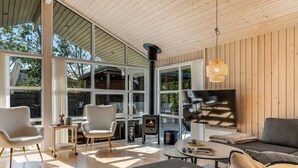 Een moderne woonkamer met een open haard, grote ramen en een gezellige zithoek.