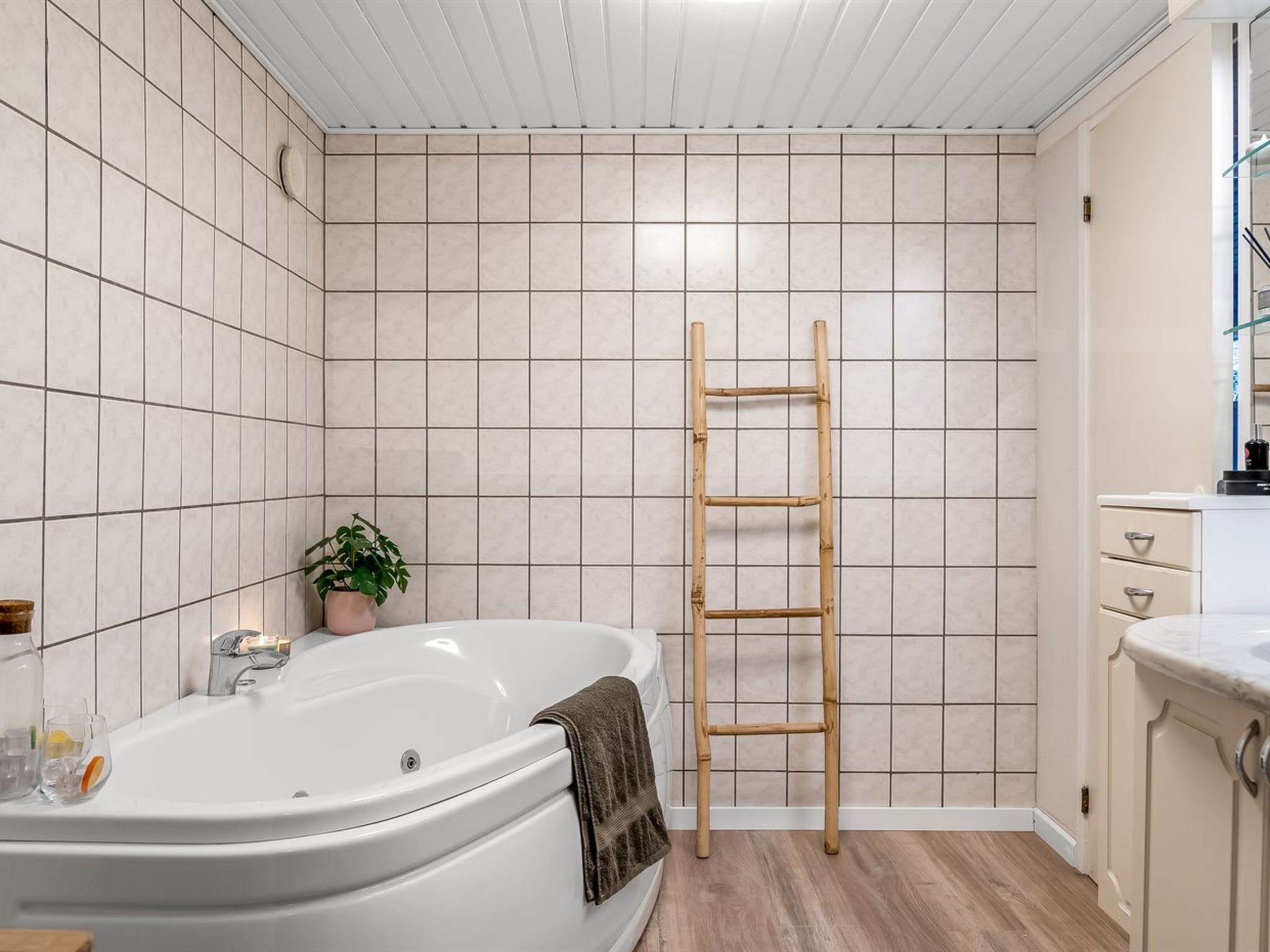 A bathroom with a bathtub, a wooden ladder, and a potted plant.