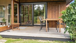 A modern outdoor patio with a wooden deck, a table, and chairs.