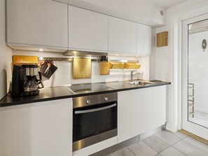 A modern kitchen with white cabinetry, stainless steel appliances, and a black countertop.