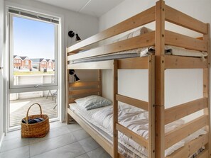 A bunk bed room with a window, a lamp, and a wicker basket.