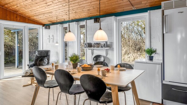 A modern kitchen with a wooden ceiling, a white refrigerator, and a dining area with black chairs and a wooden table. - "Askatla" - 800m from the sea by Interhome (Ringkøbing)