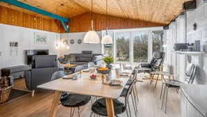 A modern, open-plan living space with a wooden ceiling, a dining area with a table and chairs, and a seating area with sofas and a TV. - "Askatla" - 800m from the sea by Interhome (Ringkøbing)