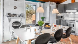 A modern kitchen with a dining area, featuring a white table, black chairs, and pendant lighting. - "Askatla" - 800m from the sea by Interhome (Ringkøbing)