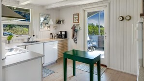 Eine moderne Küche mit großem Fenster, einem grünen Tisch und einer Tür, die nach draußen führt.