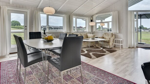 A spacious dining area with a high ceiling, large windows, and a view of the outdoors.