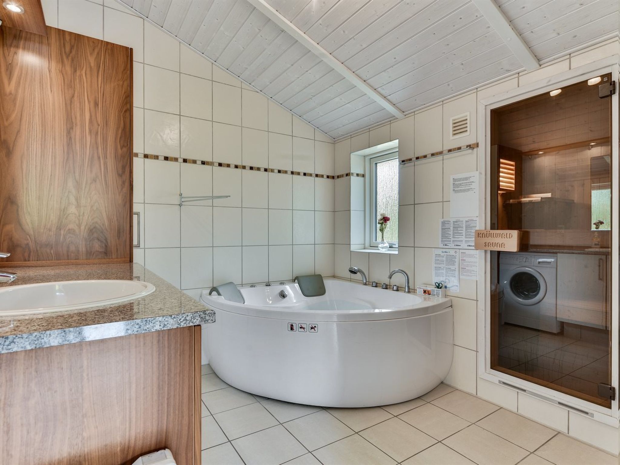 Une salle de bain moderne avec une baignoire sur pieds, un lavabo et un lave-linge encastré.